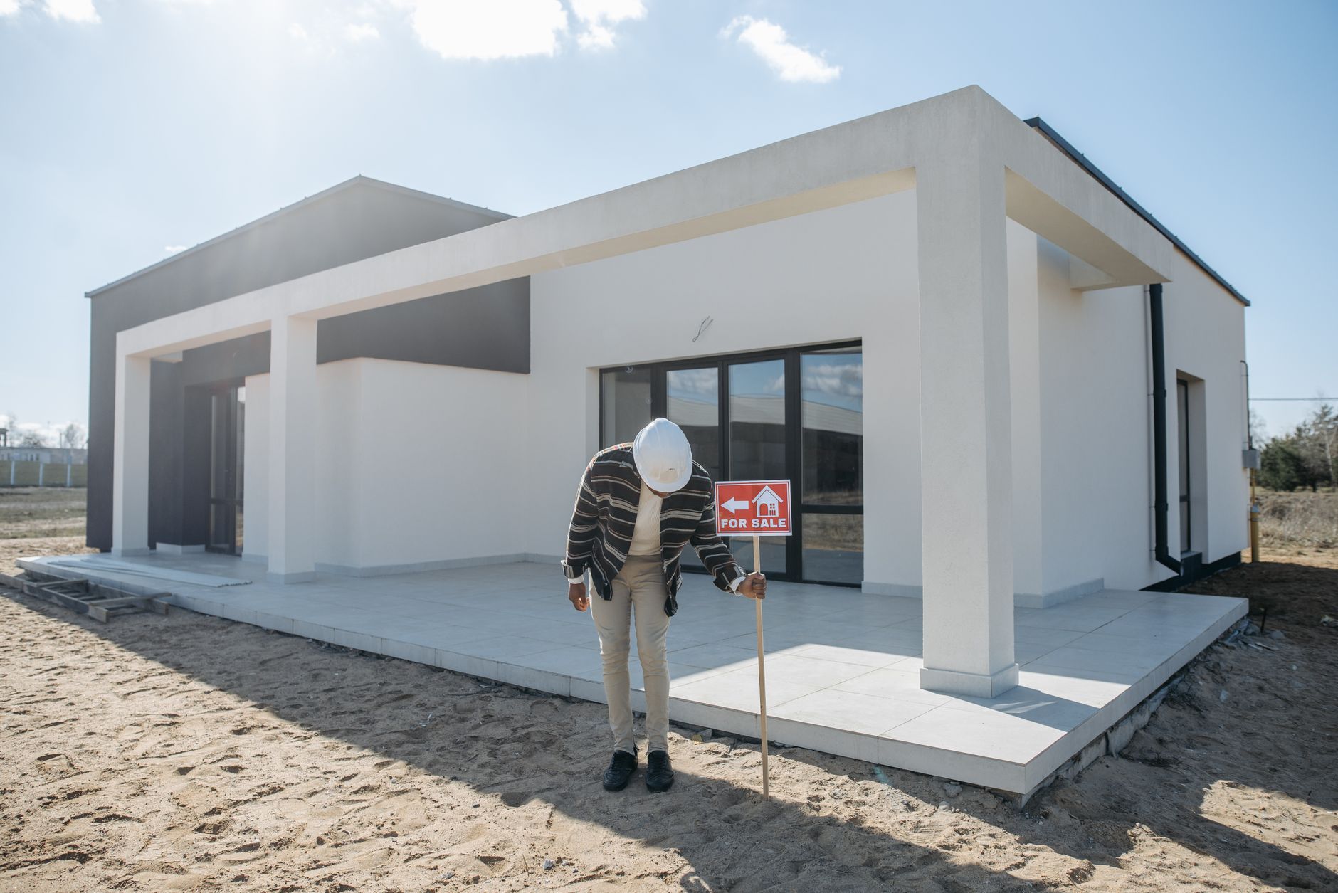 Corretor imobiliário instalando placa de venda na frente de casa
